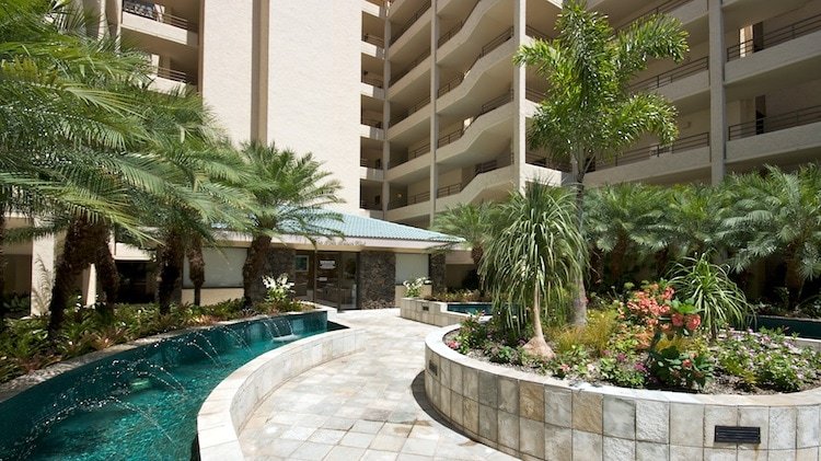 A welcoming entrance at Polo Beach Club with mature landscape and water feature